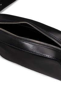 Black leather pouch with a smooth texture, featuring a silver zipper and stitching detail along the edge. Opens to reveal a fabric-lined interior.