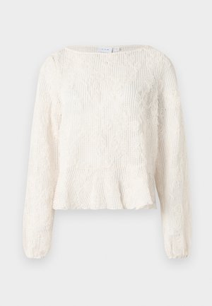 Jersey de punto blanco de manga larga con patrón de encaje floral y un dobladillo ligeramente acampanado, exhibido sobre un fondo neutro.