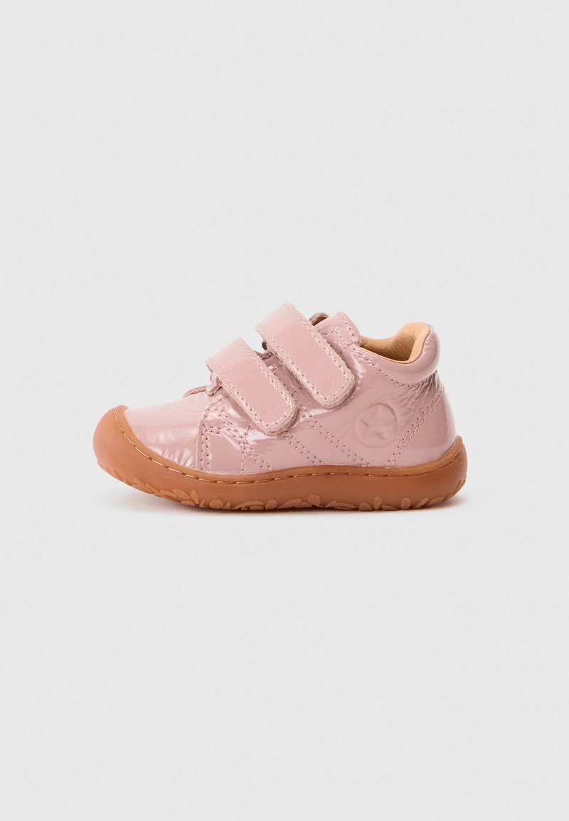 Chaussure rose pour tout-petit avec deux brides velcro et une semelle en caoutchouc marron, vue de côté sur un fond gris clair.