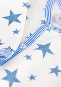Blaue Stoff mit Sternmuster auf weißem Hintergrund, mit einer gestreiften blauen Knopfleiste. Die weiche Textur ist im Material sichtbar.