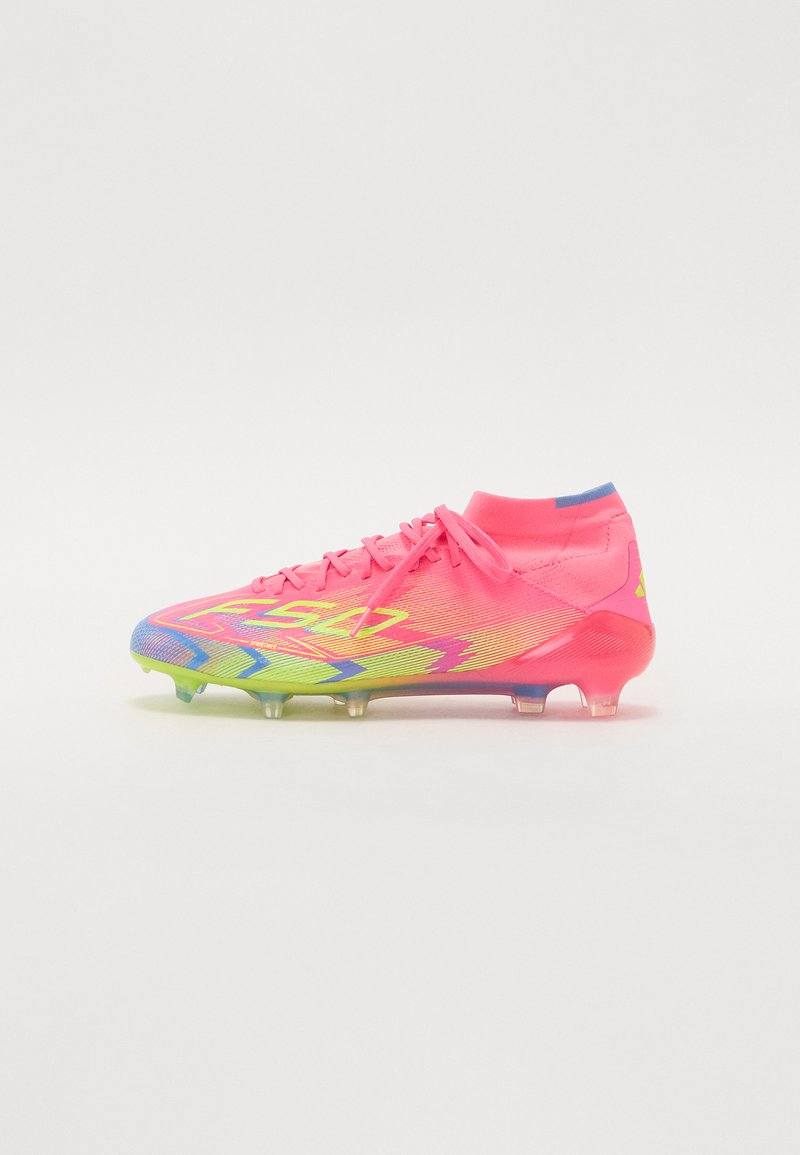Chuteiras de futebol com um cabedal rosa, apresentando um degradé de azul para verde na sola. Design texturizado e cravos transparentes para aderência.