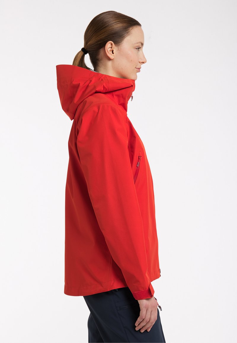 Červená voděodolná bunda s kapucí, bočním zipovým kapsou a elastickými manžetami, vyrobená z hladkého, lehkého materiálu, s volným střihem.