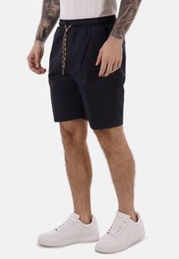 Bermuda da uomo blu navy in un materiale leggero, con vita elasticizzata e cordoncino. Abbinate a sneakers bianche.