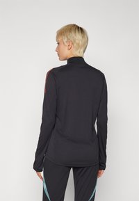Svart langermet topp med høy krage, med røde skulderstriper, glatt tekstur og tettsittende design. Ingen synlige logoer eller mønstre.