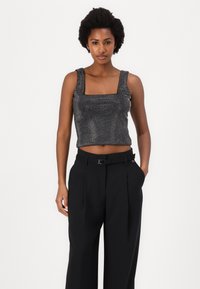 Must mustriga mustriga tank top ruutja kaelusega, kaunistatud väikeste hõbedaste nögudega. Kombineeritud kõrge talje ja vöökohaga mustade pükstega.