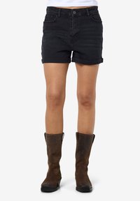 Black denim shorts with rolled cuffs, featuring a button closure and front pockets, paired with knee-high brown leather boots.