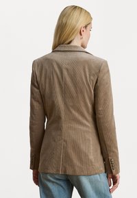 Blazer in corduroy marrone con vestibilità su misura, collo a revers e polsini con bottone, caratterizzato da una texture a coste verticali e una ventatura singola sul retro.