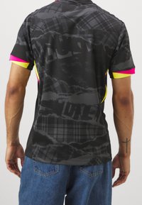 Camicia a maniche corte nera con un sottile motivo a quadri, arricchita da accenti neon rosa e giallo sulle maniche. Texture del tessuto liscia.