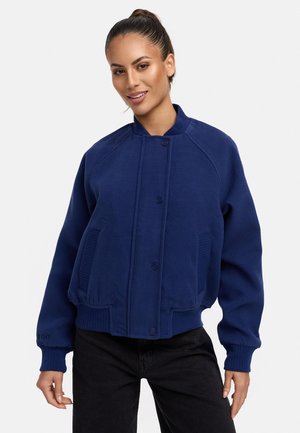Veste bomber bleu marine en tissu doux, avec un col et des poignets côtelés, une fermeture à boutons sur le devant et des poches latérales. Design à la coupe relaxée.