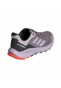 Chaussure de sport grise et lavande avec un dessus en maille texturée, trois rayures blanches et une semelle extérieure rouge-orange. Dispose d'une semelle rembourrée.