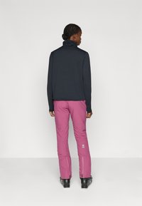 Marineblauw longsleeve shirt met een gestructureerde afwerking en hoge kraag, gecombineerd met fuchsia broek met ritssluitingen bij de enkels en logo-details.