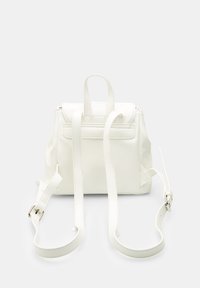 Hvid faux læder rygsæk med justerbare stropper, glat tekstur, struktureret form og frontklaplukning. Har et minimalistisk design.