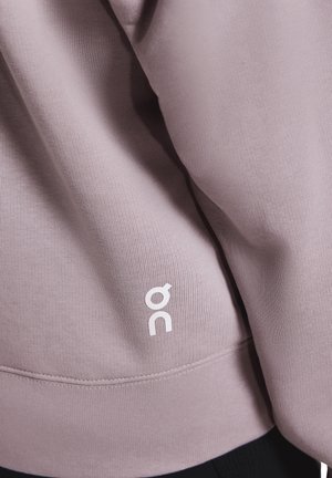 Lichtpaarse sweatshirt van zachte stof, met een geribbelde textuur en een wit logo aan de zoom. Eenvoudig ontwerp met een ontspannen pasvorm.