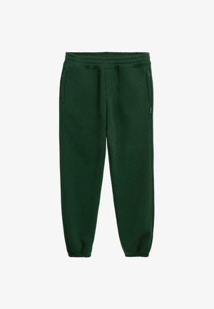 Zelené tepláky vyrobené z měkké tkaniny mají elastický pás, manžety u kotníků a dvě postranní kapsy pro větší funkčnost.