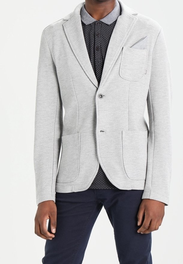 Hellgrauer Blazer mit strukturierter Oberfläche, ausgestattet mit zwei Fronttaschen, einem Einzelknopfverschluss und einem Kerbkragen, getragen über einem dunklen gepunkteten Hemd.