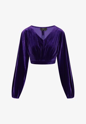 Alyvuogių aksomo trumpa palaidinė su V formos iškirpte, raukinių detalėmis krūtinės srityje ir ilgomis burbulinėmis rankovėmis. Lygus tekstūra ir turtinga spalva.