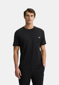 T-shirt nera a girocollo in tessuto morbido, con un piccolo logo sul petto. Maniche corte, vestibilità rilassata e texture liscia.