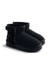 Stivaletti neri realizzati in morbido suede con dettagli in frange e borchie dorate sui lati. Suola in gomma nera con una finitura testurizzata.