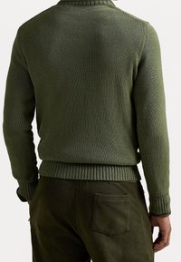 Maglione a maglia verde oliva con colletto e polsini a coste, caratterizzato da una finitura testurizzata. Abbinato a dei pantaloni verdi oliva coordinati, con una tasca posteriore.