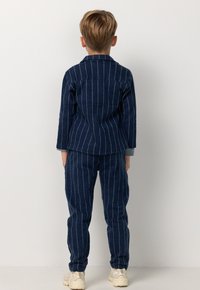 Marine gestreepte two-piece outfit voor kinderen, gemaakt van gestructureerde stof. Het shirt heeft een kraag en de broek heeft een losse pasvorm.