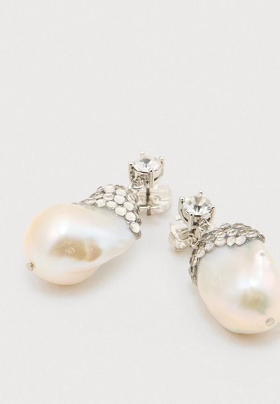 Ζευγάρι ασημένια σκουλαρίκια με μεγάλες ακανόνιστες πέρλες και μικρούς στρογγυλούς κρυστάλλους από πάνω, τοποθετημένα σε λευκό φόντο.