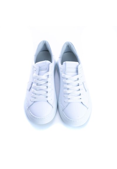 Baskets en cuir blanc avec des lacets plats, bout arrondi, semelle en caoutchouc texturé et minimalisme de la marque sur la languette.