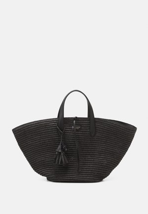 Bolso tote ancho tejido negro con dos asas cortas y adorno de borlas en la parte frontal sobre fondo liso.