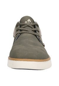 Grön nätträningssko med beige accenter, rund tå och platt vit sula. Har grå snören och en texturerad ovandel för andningsförmåga.