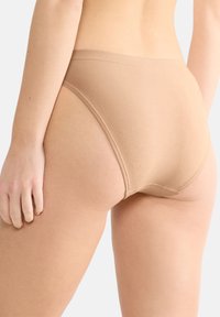 Beige Baumwollmischunterwäsche mit glatter Textur, hohen Beinausschnitten und einem nahtlosen Design mit minimalistischer Naht.