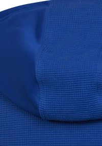Tessuto blu con un motivo testurizzato e design a griglia. La superficie liscia nella parte superiore contrasta con la sezione inferiore testurizzata.