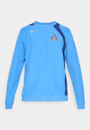 Sweatshirt azul claro com mangas longas, detalhes em azul marinho nos ombros, logotipo da Nike em amarelo e emblema da equipe na parte da frente. Tecido suave.