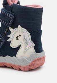 Botte de marin pour tout-petit avec doublure rose, semelle grise et rose, sangle Velcro et écusson de licorne avec crinière irisée sur le côté.