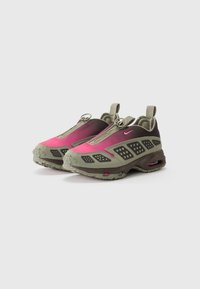 Nike-sko med gradientdesign, i rosa og mørk olivengrønn. Teksturert gummisåler og integrerte løkker for enkel påkledning.