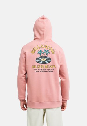 Persona che indossa una felpa con cappuccio rosa con un logo Billabong Island Beats con palme e un disco in vinile sulla schiena.