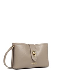Sac à main en cuir gris avec une forme arrondie, des détails en métal doré et une sangle fine. Le nom de la marque "Lancaster" est embossé sur le devant.