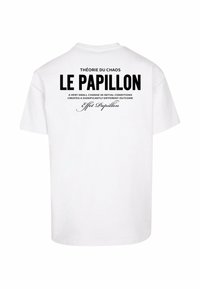 Hvid bomulds t-shirt med sort tekst på ryggen, herunder "THÉORIE DU CHAOS" og "LE PAPILLON," med et dekorativt skrifttype nedenfor.