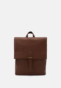 Un sac à dos en cuir marron avec un rabat de fermeture, une sangle à boucle et une poignée supérieure. Texture lisse, design simple et sans motifs visibles.