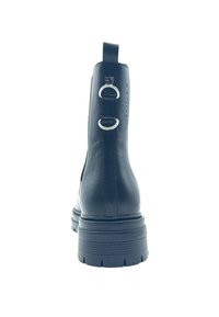 Botte de cheville noire avec une finition en cuir lisse, dotée d'une languette à l'arrière et de deux anneaux en argent comme accents. Semelle en caoutchouc épaisse avec un design cranté.