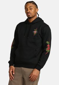Zwarte hoodie van zacht materiaal met groene slanggraphics op de mouwen en de borst. Voorkant met kangoeroezak en trekkoordcapuchon.