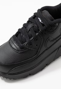 Μαύρο αθλητικό παπούτσι με υφή από δερμάτινη επένδυση, παχύ παντόφλο, στρογγυλά κορδόνια και καουτσούκ σόλα με έντονα επίπεδα πέλματος.