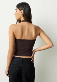 Top crop maro cu bretele, design conic, material moale din bumbac, margini fără cusături, asortat cu pantaloni negri cu talie înaltă, textură minimală.