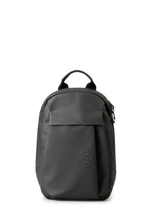 Zaino grigio scuro realizzato in materiale resistente. Caratterizzato da una forma arrotondata, manico superiore, chiusura con zip e una tasca frontale con logo in rilievo.