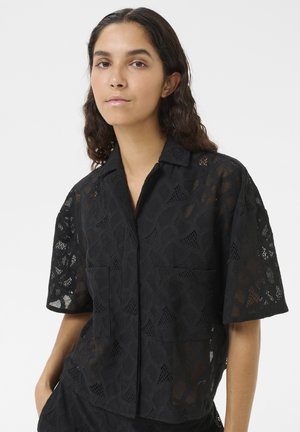 Chemise noire à manches courtes avec un motif texturé en tissage ouvert, deux poches avant, un col à encoche et une coupe ample.