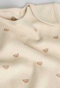 Body cremă cu dungi, imprimat cu fețe mici de ursuleț în nuanță maro deschis; textură moale, decolteu rotund și mâneci scurte.