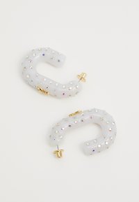 Fermagli bianchi translucidi a forma di "C," adornati con strass multicolori e dotati di accessori in oro per una chiusura sicura.
