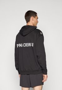 Felpa con cappuccio nera caratterizzata da una grande stampa bianca "PUMA CREW'48" sul retro. Il tessuto sembra morbido con una vestibilità comoda.
