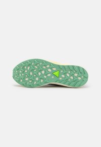 Suela de zapatilla para trail running con un diseño de goma verde texturizada, un dibujo de banda de rodadura y un acento lateral amarillo.