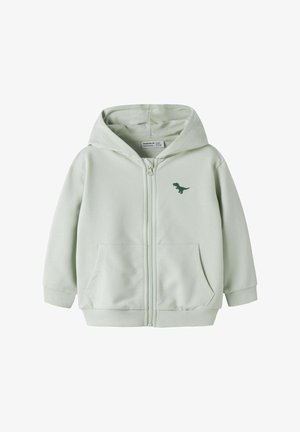Sweat à capuche zippé gris clair pour enfants avec poches avant, une capuche et un petit motif de dinosaure vert foncé sur le côté gauche de la poitrine.