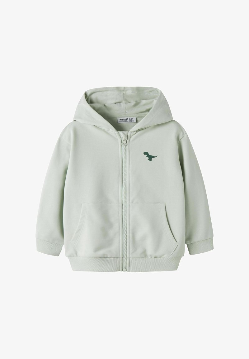 Ανοιχτό γκρι παιδικό φούτερ με φερμουάρ, μπροστινές τσέπες, κουκούλα και μικρό σκούρο πράσινο γραφικό δεινόσαυρου στο αριστερό μέρος του στήθους.