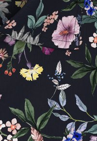 Donkere stof met een bloemmotief bestaande uit roze, gele, blauwe en witte bloemen, groene bladeren en een subtiele textuurafwerking.
